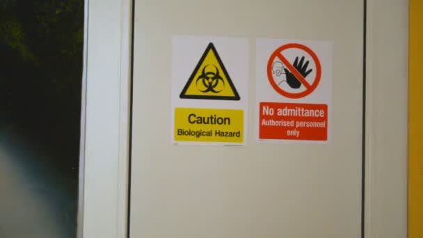Caution Biological Hazard and No Admittance warning danger signs on the door entrance to the laboratory - Footage, Video