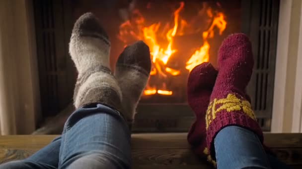 Closeup slow motion footage of couple wearing knitted woolen socks relaxing by the fireplace - Footage, Video