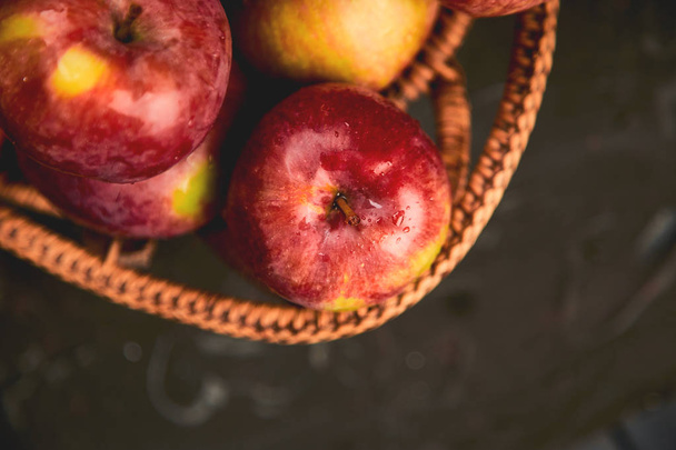 Свежие органические красные яблоки в корзине на черном фоне. Осенний урожай. Плоский лежал. Вид сверху. Копирование пространства
.  - Фото, изображение