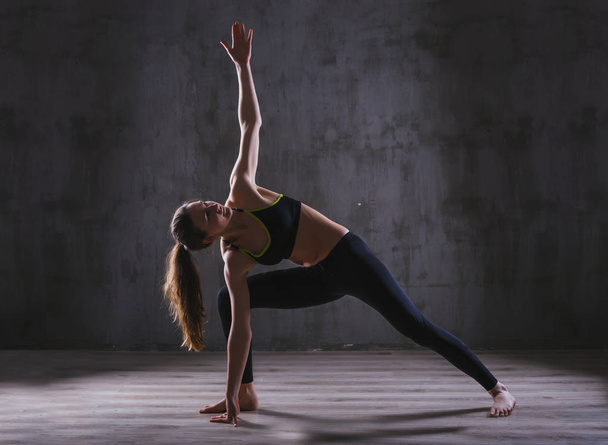 Fitness woman training in dark studio. Young girl posing on black background - Zdjęcie, obraz