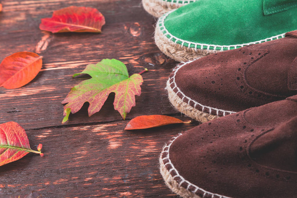 Коричневий і зелений людина замшеві чоботи espadrilles на дерев'яні фону з листя. Восени або взимку взуття. дві пари. Укласти з плоским.  - Фото, зображення