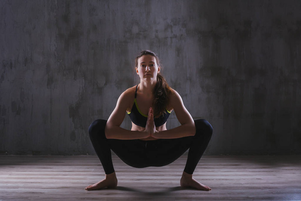 Fitness woman training in dark studio. Young girl posing on black background - Fotografie, Obrázek