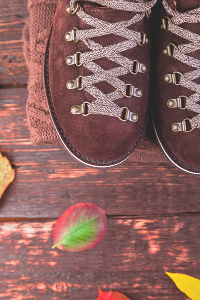 Muž hnědé semišové boty s svetr na dřevěné pozadí s listy. Podzimní nebo zimní boty. Oblečení. - Fotografie, Obrázek