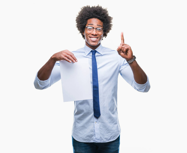 Афро-американец с пустым бумажным контрактом на изолированном фоне, удивленный идеей или вопросом, указывающим пальцем со счастливым лицом, номер один
 - Фото, изображение