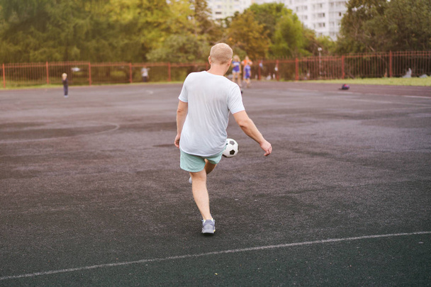 активный образ жизни в современном городе - спортивный человек, играющий с футбольным мячом на стадионе
 - Фото, изображение
