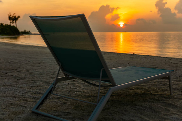 bequemer Strandkorb auf einsamen Seeschuhen bei Sonnenuntergang   - Foto, Bild
