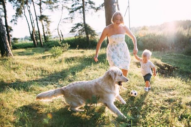 Молода, симпатична мати з сином і собакою активно і весело проводять час на природі
. - Фото, зображення