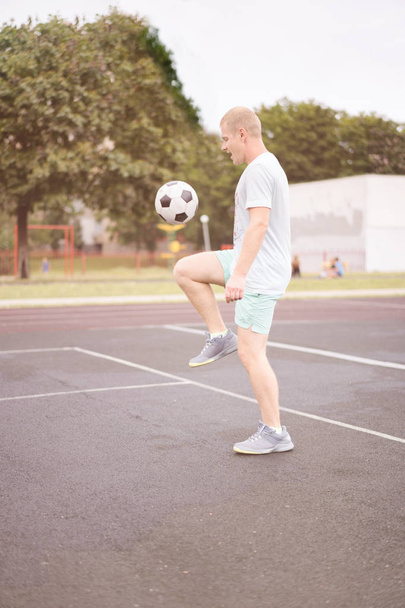 estilo de vida activo en una ciudad moderna - hombre deportivo jugando con una pelota de fútbol en el estadio
 - Foto, Imagen