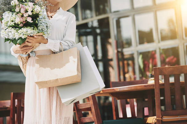Cropped image of fashionable woman flowers and paper-bags - Photo, Image