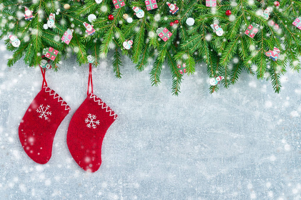 Κόκκινα Χριστούγεννα κάλτσες με κλαδιών χριστουγεννιάτικο δέντρο και το χιόνι σε γκρι φόντο. Αντιγράψτε το χώρο, το top view. Ευχετήρια κάρτα. - Φωτογραφία, εικόνα