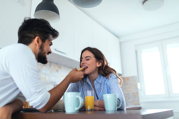 A young man feeding his beautiful girlfriend in the morning. - Foto, imagen
