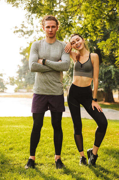 Photo of happy young people man and woman 20s in sportswear training together in green park during sunny summer day - Foto, Imagen