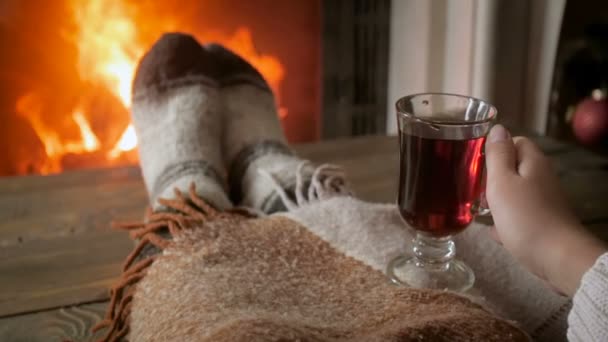 Closeup slow motion video of woman relaxing by the fireplace at night and drinking hot tea - Footage, Video