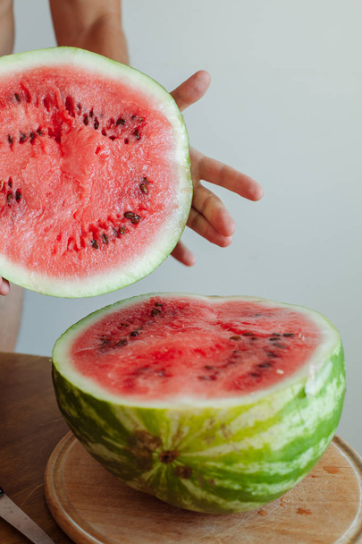 Man's hand cutting a watermelon on the table - Fotografie, Obrázek
