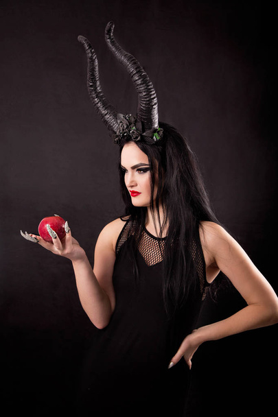 An apple in the hands of a horned witch - Fotoğraf, Görsel
