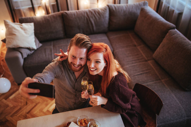 Young couple making a selfie while holding Champagne flutes - Photo, image