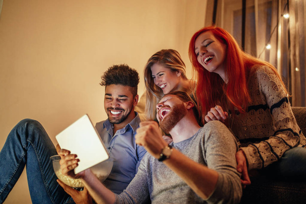 Four friends looking at a tablet laughing - Foto, imagen