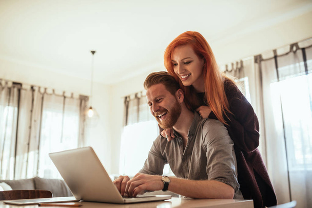 Young smiling couple using laptop - Fotó, kép