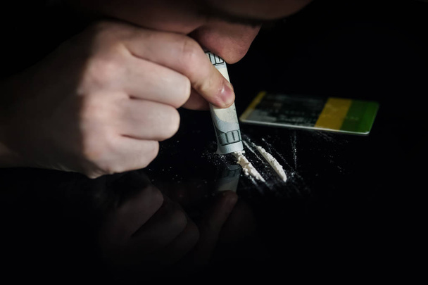 Un giovanotto che prepara cocaina per annusare usando una carta di credito. Nocivo abitudine mortale
. - Foto, immagini