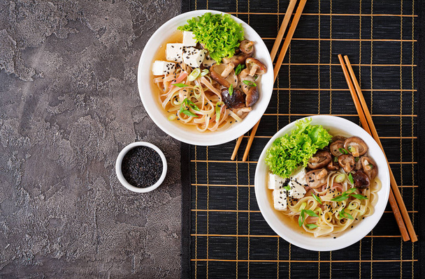 Vegan noodle soup with tofu cheese, shiitake mushrooms and lettuce in white bowl. Asian food. Top view. Flat lay - Photo, Image