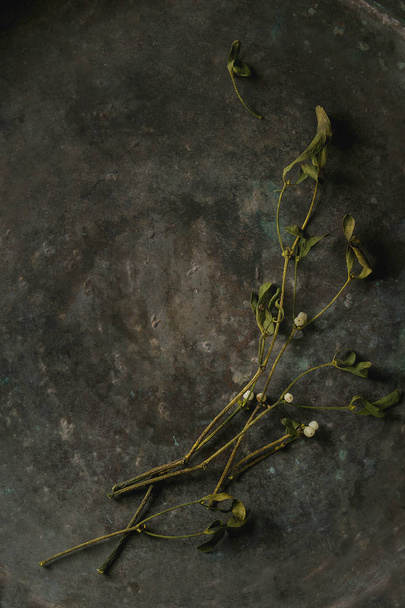 Традиційні різдвяні рослини тумблерні гілки з ягодами на старому фоні темного металу. Вид зверху, простір
 - Фото, зображення