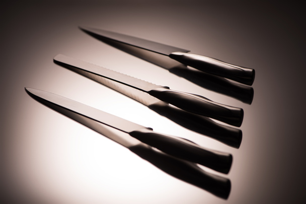 close-up view of various kitchen knives on grey - Фото, зображення