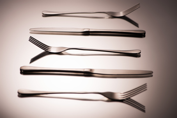 close-up view of shiny forks and knives arranged on grey    - Fotografie, Obrázek