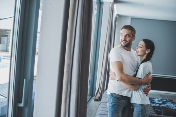 smiling adult man hugging attractive girlfriend at home - Photo, Image