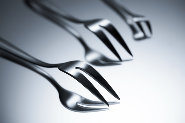 close-up view of forks with two tines reflected on grey  - Φωτογραφία, εικόνα