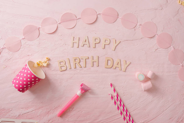 Fond de fête d'anniversaire, bordure de confettis, bonbons, sucettes et cadeau sur la surface rose, espace de copie, vue dessus
 - Photo, image