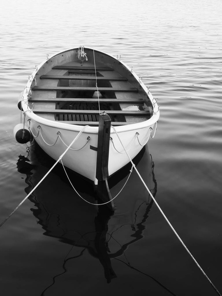 Monochrome image of an empty rowboat in the water - Photo, Image