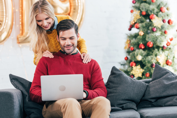 happy couple using laptop together at home on christmas - 写真・画像