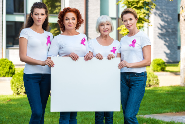 kobiety z wstążkami świadomości raka piersi przytrzymanie puste pusty transparent i uśmiecha się do kamery  - Zdjęcie, obraz