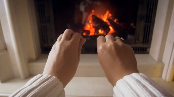 Zpomalené záběry mladé ženy třením a táhnoucí se k hořící oheň v krbu v domě její studené ruce - Záběry, video