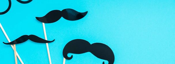 Creative long wide banner top view retro stylish black paper photo booth props moustaches turquoise background copy space. Men health awareness month fathers day masculinity concept blog social media - Foto, imagen