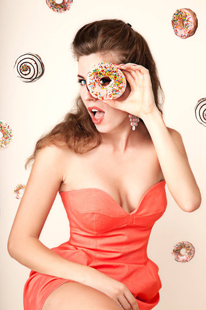 High Fashion model woman posing in studio with donut in colorful bright lights, portrait of stylish party girl with trendy make-up, haircut. Art design colorful make up. On colourful vivid background. - Photo, Image