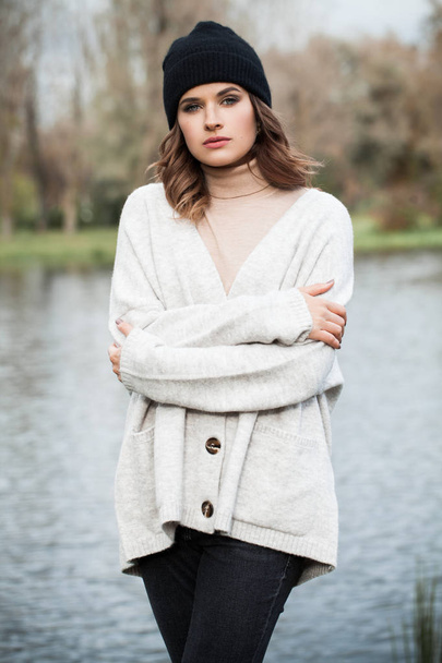 Attractive young woman in white cardigan and black cap outdoor - Fotografie, Obrázek