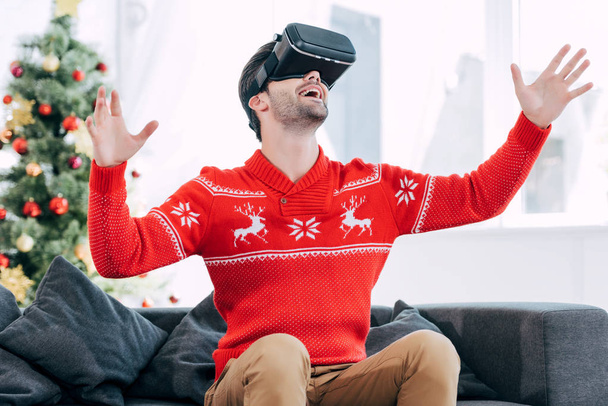 ενθουσιασμένος ο άνθρωπος χειρονομίες και τη χρήση του σετ κεφαλής εικονικής πραγματικότητας κατά τη διάρκεια της παραμονή Χριστουγέννων - Φωτογραφία, εικόνα