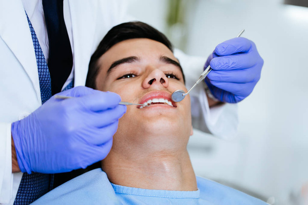 Young attractive man receiving a dental treatment. Close up shot. - Photo, Image