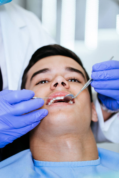 Young attractive man receiving a dental treatment. Close up shot. - Foto, Imagen