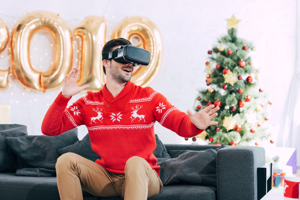 Χαμογελαστός άνθρωπος χρησιμοποιεί σετ κεφαλής εικονικής πραγματικότητας κατά το νέο έτος 2019 - Φωτογραφία, εικόνα