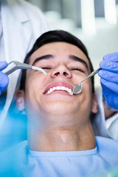 Young attractive man receiving a dental treatment. Close up shot. - Фото, зображення
