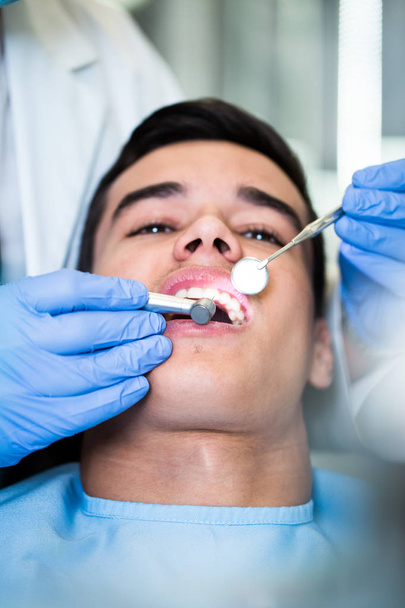 Young attractive man receiving a dental treatment. Close up shot. - Foto, imagen
