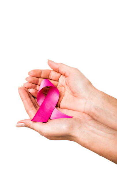 白、乳房癌意識概念で隔離の手でピンクのリボンを保持している女性のクロップ撮影 - 写真・画像