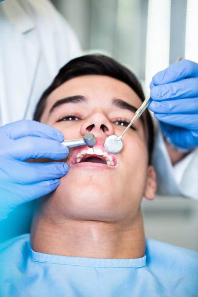 Young attractive man receiving a dental treatment. Close up shot. - Photo, image