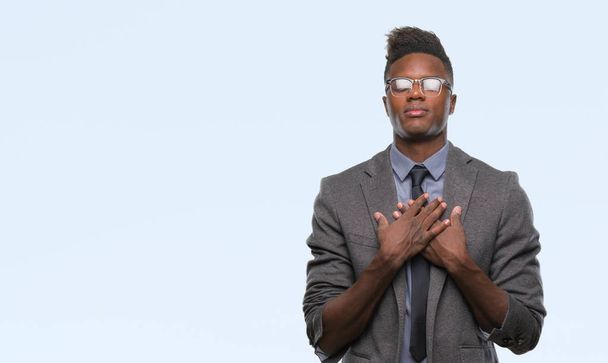 Young african american business man over isolated background smiling with hands on chest with closed eyes and grateful gesture on face. Health concept. - Photo, Image