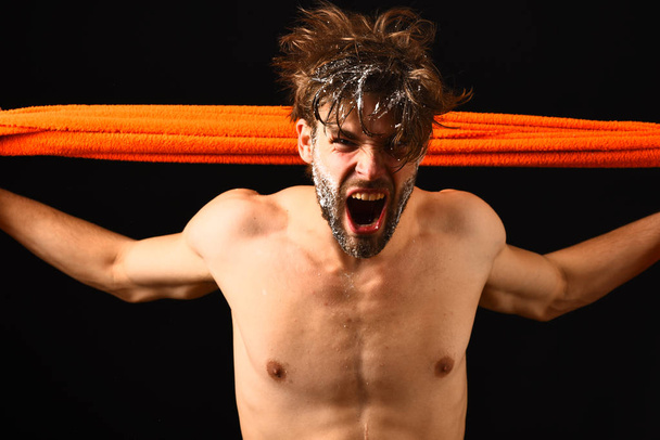 Man bearded tousled hair covered with foam or soap suds. Wash off foam with water carefully. Water is over. Man with orange towel ready to take shower. Macho attractive nude guy black background - Фото, зображення