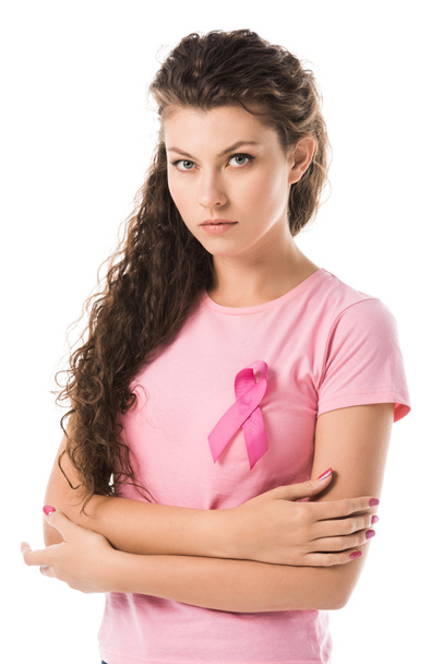 young woman with pink ribbon standing with crossed arms and looking at camera isolated on white, breast cancer concept  - Photo, Image