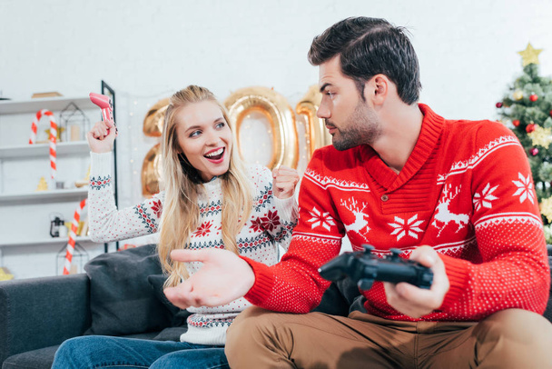 joven pareja jugando video juego con joysticks en la víspera de Navidad
 - Foto, imagen