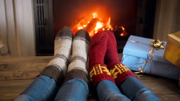 Αργή κίνηση μήκος σε πόδηα των δύο ανθρώπων που φορούν πλεκτές μάλλινες κάλτσες ξεκούρασης δίπλα στο τζάκι στο σπίτι - Πλάνα, βίντεο